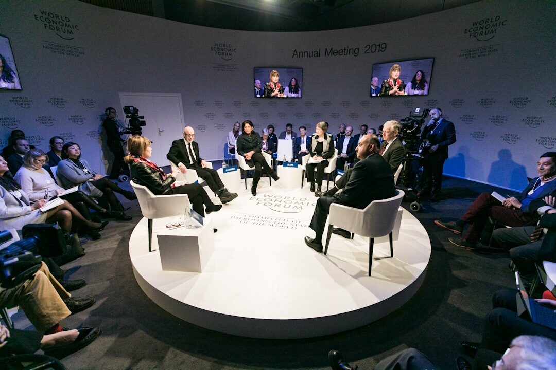 Journalists seated in a press conference hall with cameras